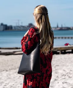Skuldertaske: Anne fra Ida Brink Leather i sort kernelæder, set på stranden ved Bellevue i Aarhus.
