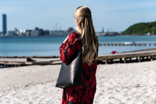 Skuldertaske: Anne fra Ida Brink Leather i sort kernelæder, set på stranden ved Bellevue i Aarhus.