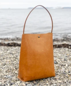 Skuldertaske i læder fra Ida Brink Leather: Anne i natur med patina og klassisk hank - på stranden ved Helgenæs