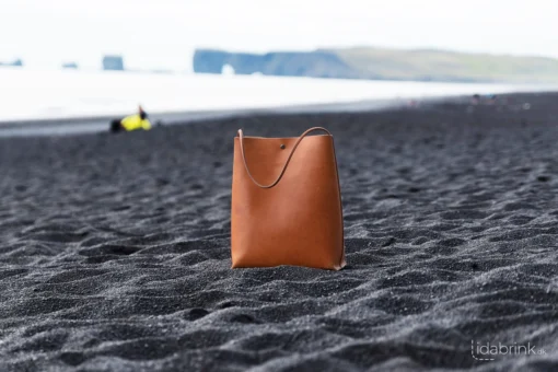 Skuldertaske i læder fra Ida Brink Leather: Anne med patina og klassisk hank på Reynisfjara-stranden i Island